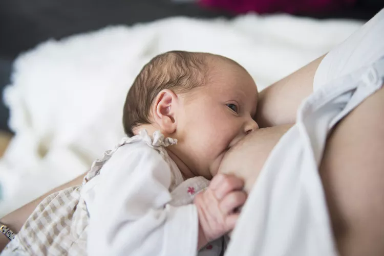 “Newborn infant breastfeeding and latching onto mother’s breast.”